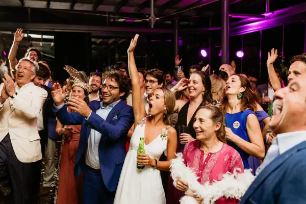 Wedding guests cheering and singing with the bride on a packed dance floor