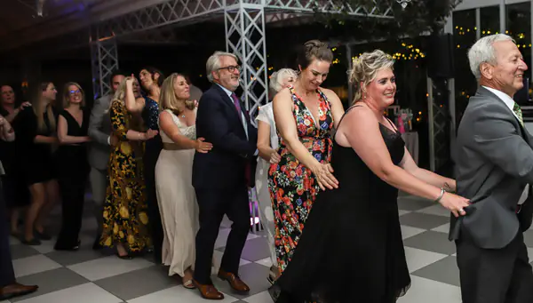 Wedding guests dancing in a conga line on a chequered dance floor in Paarl